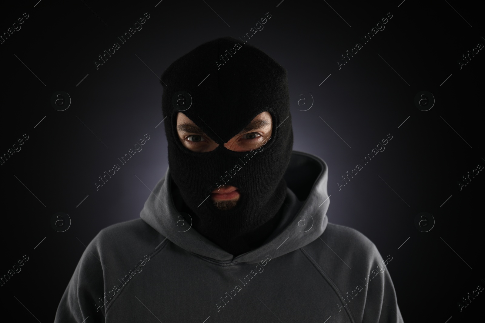 Criminal man in mask on dark background Photo of Criminal man in mask on dark background