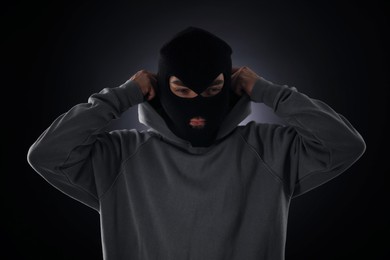 Photo of Criminal in mask and hood on dark background