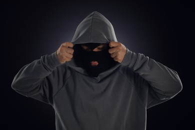 Photo of Criminal in mask and hood on dark background
