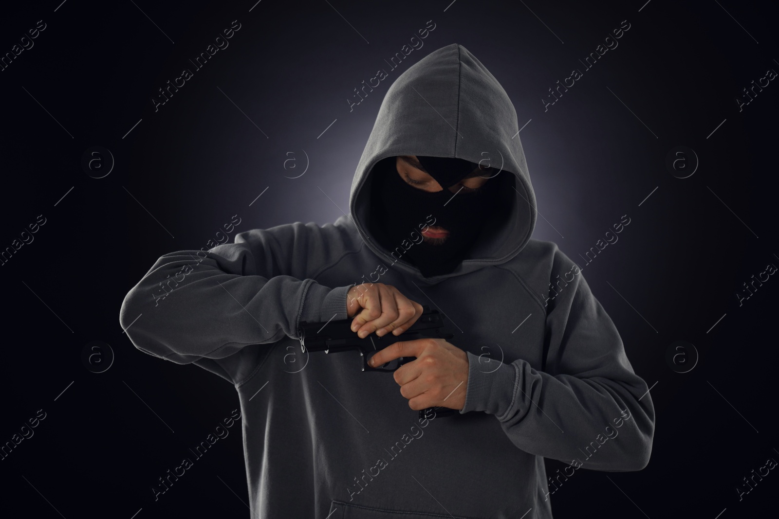 Criminal in mask with gun on dark background Photo of Criminal in mask with gun on dark background