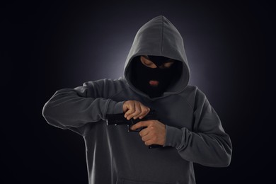 Photo of Criminal in mask with gun on dark background