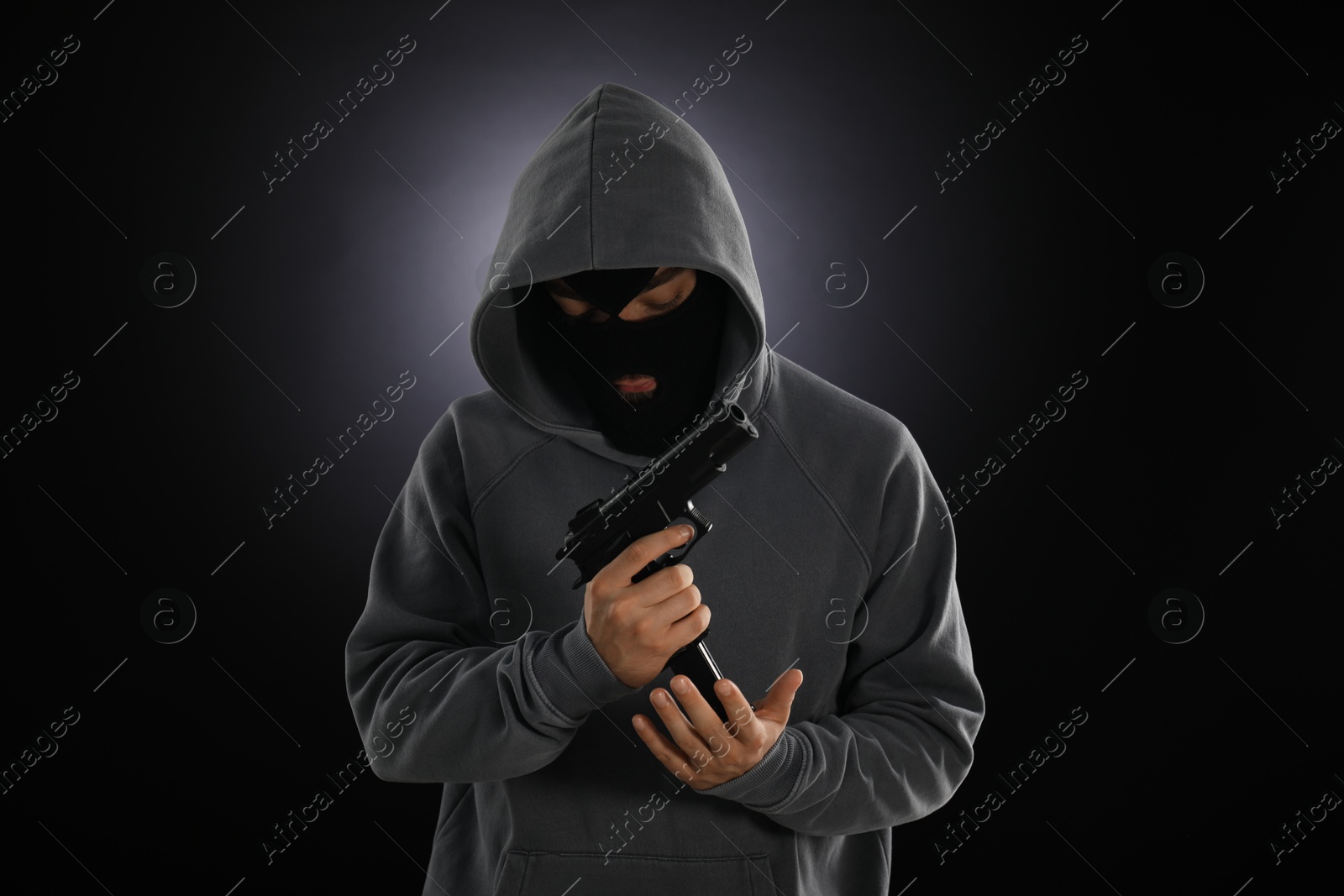 Criminal in mask with gun on dark background Photo of Criminal in mask with gun on dark background