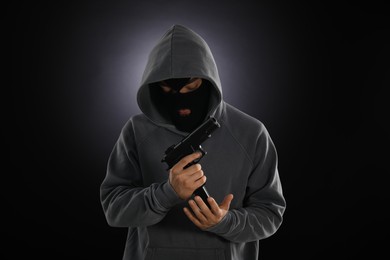 Photo of Criminal in mask with gun on dark background