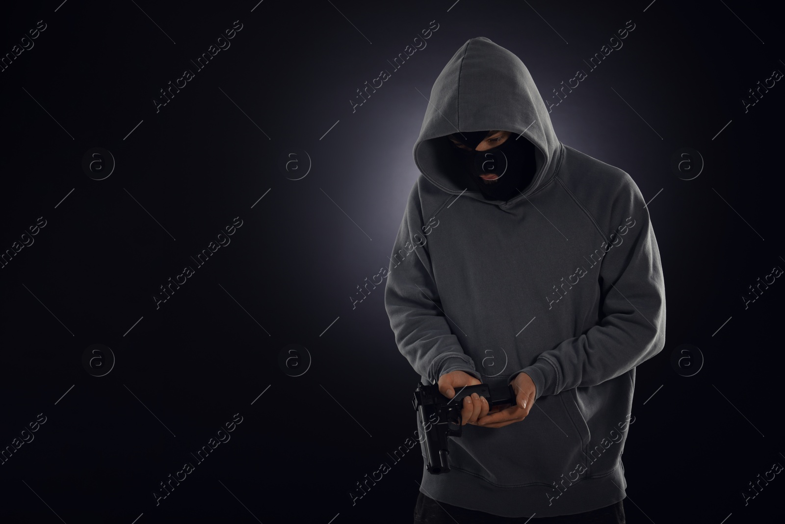 Criminal in mask with gun on dark background. Space for text Photo of Criminal in mask with gun on dark background. Space for text