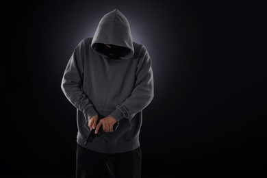 Photo of Criminal in mask with gun on dark background. Space for text