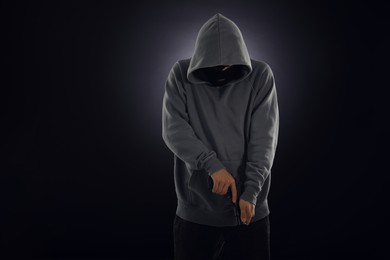 Photo of Criminal in mask with gun on dark background. Space for text