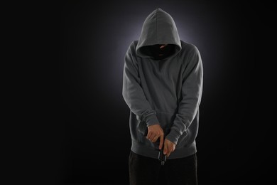 Photo of Criminal in mask with gun on dark background. Space for text