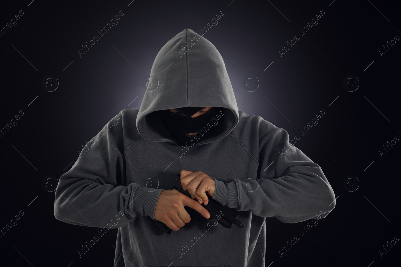 Criminal in mask with gun on dark background Photo of Criminal in mask with gun on dark background