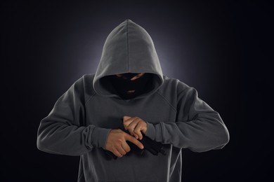 Photo of Criminal in mask with gun on dark background