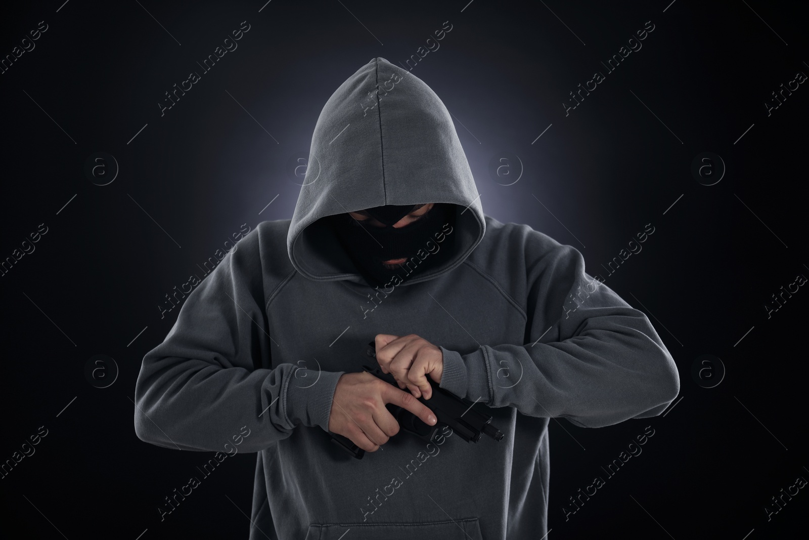 Criminal in mask with gun on dark background Photo of Criminal in mask with gun on dark background