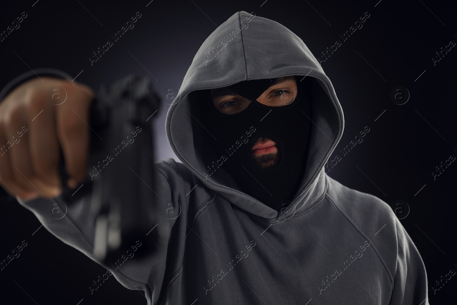 Criminal in mask with gun on dark background, selective focus Photo of Criminal in mask with gun on dark background, selective focus