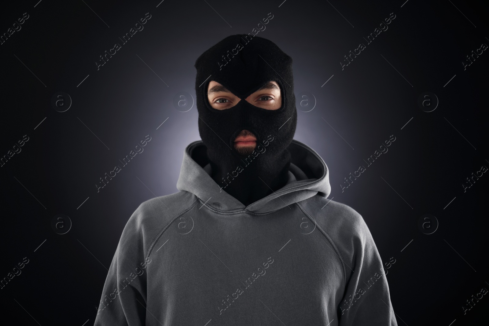 Criminal man in mask on dark background Photo of Criminal man in mask on dark background