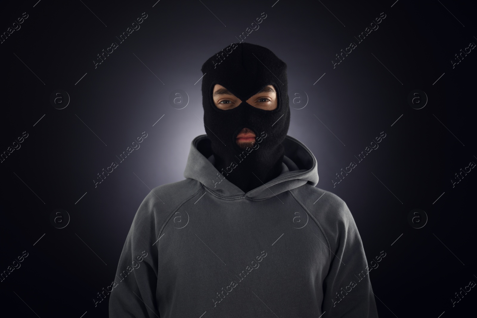 Criminal man in mask on dark background Photo of Criminal man in mask on dark background