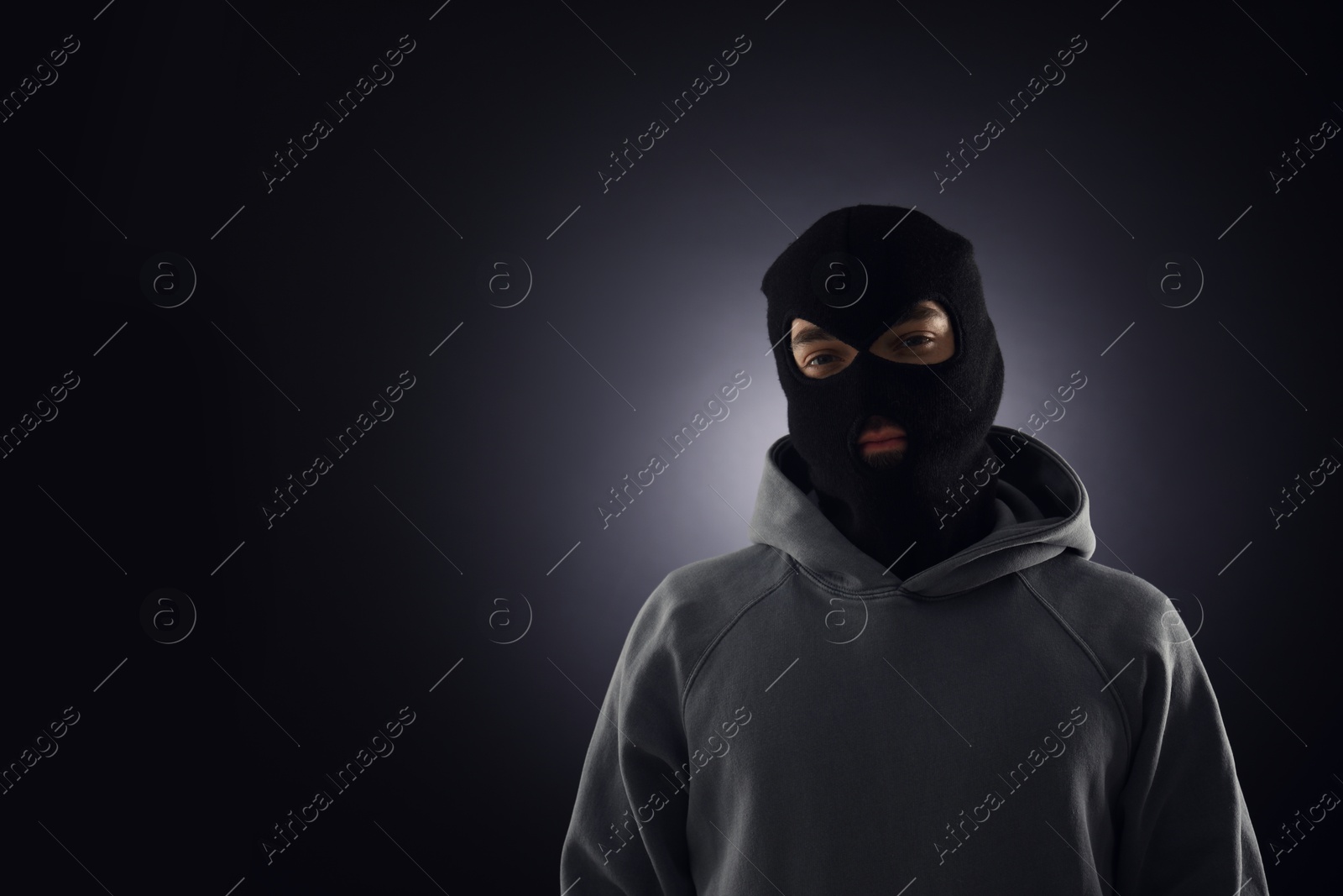 Criminal man in mask on dark background. Space for text Photo of Criminal man in mask on dark background. Space for text