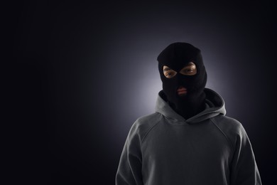 Photo of Criminal man in mask on dark background. Space for text
