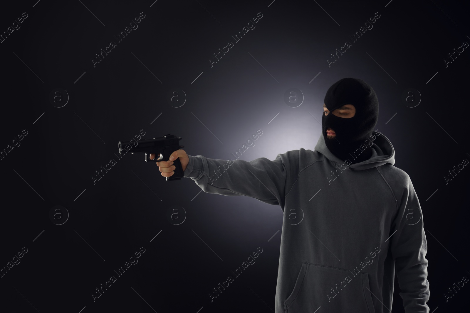 Criminal in mask with gun on dark background. Space for text Photo of Criminal in mask with gun on dark background. Space for text