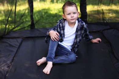 Photo of Cute little boy posing on black trampoline outdoors
