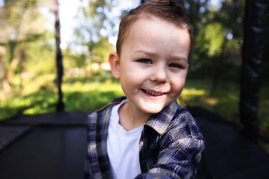 Photo of Happy little boy taking selfie on black trampoline outdoors