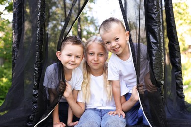 Photo of Happy children posing on black trampoline outdoors