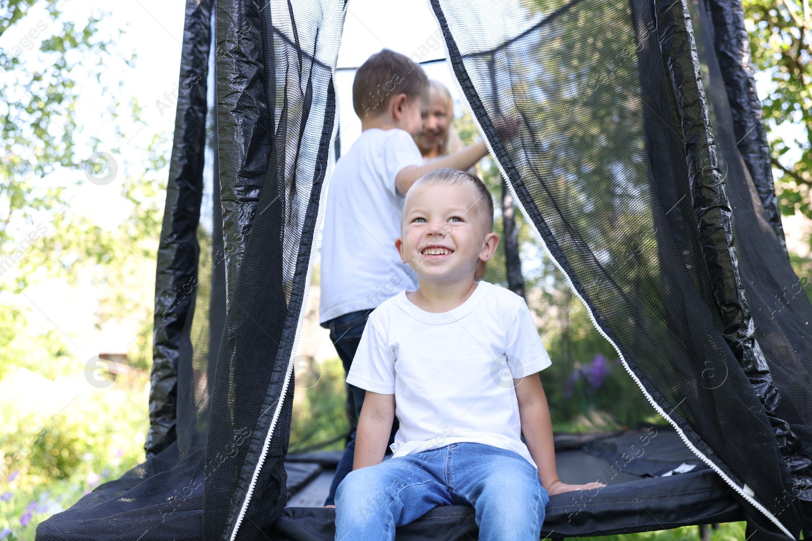 Happy little boy and his friends on black trampoline outdoors Photo of Happy little boy and his friends on black trampoline outdoors