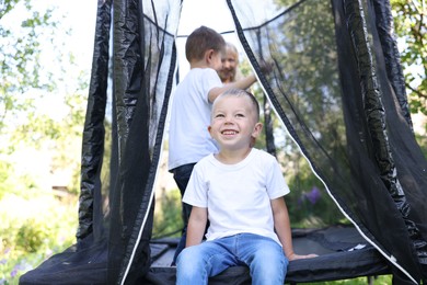 Photo of Happy little boy and his friends on black trampoline outdoors