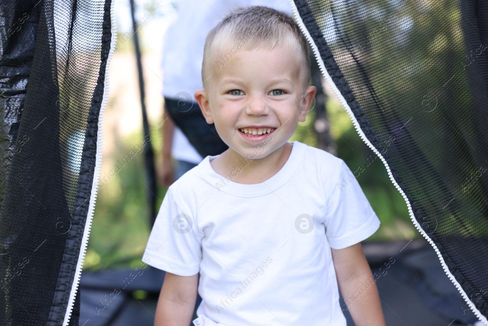 Portrait of happy little boy on black trampoline outdoors Photo of Portrait of happy little boy on black trampoline outdoors