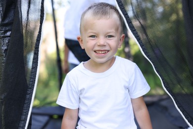 Photo of Portrait of happy little boy on black trampoline outdoors