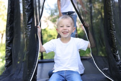 Photo of Happy little boy and his friends on black trampoline outdoors
