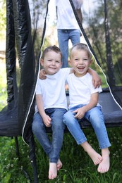 Photo of Happy little boys and his friend on black trampoline outdoors