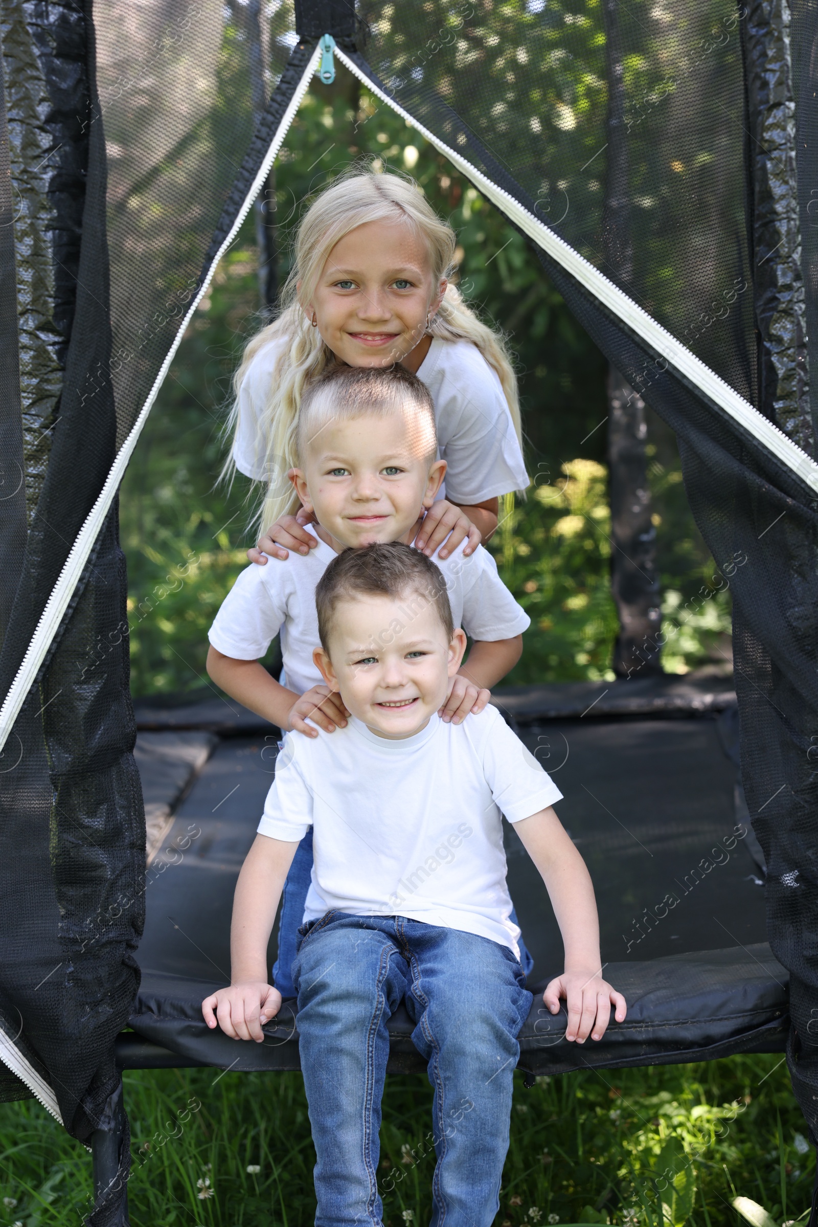 Portrait of happy children posing on black trampoline outdoors Photo of Portrait of happy children posing on black trampoline outdoors