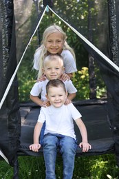 Photo of Portrait of happy children posing on black trampoline outdoors