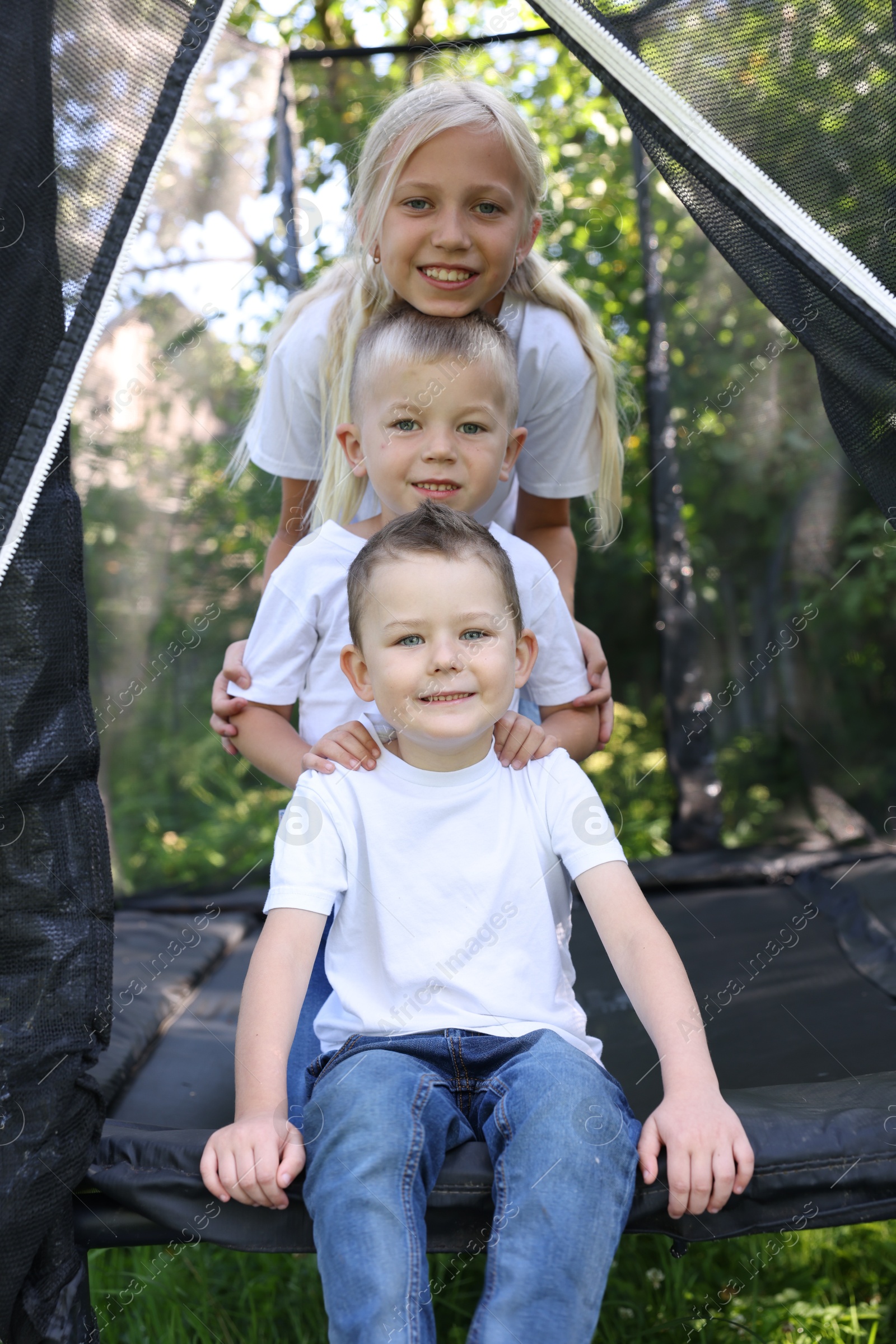 Portrait of happy children posing on black trampoline outdoors Photo of Portrait of happy children posing on black trampoline outdoors