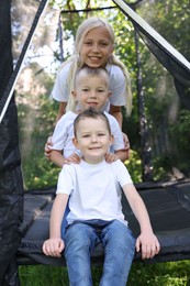 Photo of Portrait of happy children posing on black trampoline outdoors
