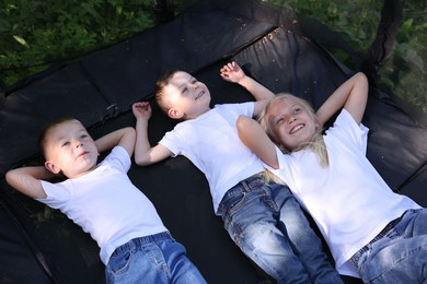 Photo of Happy children lying on black trampoline outdoors