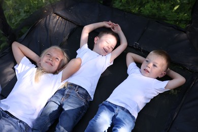 Photo of Happy children lying on black trampoline outdoors