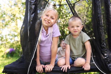 Photo of Happy little friends posing on black trampoline outdoors