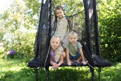 Photo of Happy little friends posing on black trampoline outdoors
