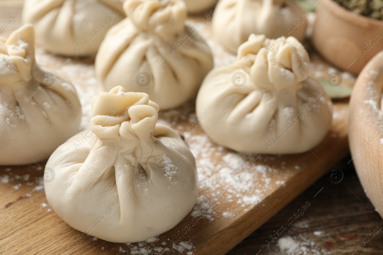 Uncooked khinkalis (dumplings) with flour on wooden table, closeup Photo of Uncooked khinkalis (dumplings) with flour on wooden table, closeup