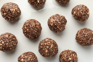 Photo of Tasty chocolate candies with nuts on white table, flat lay