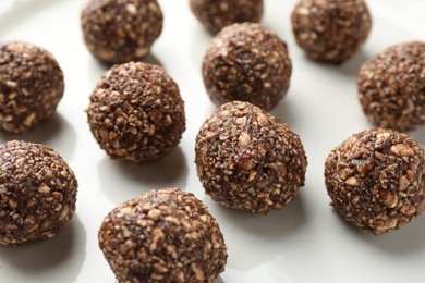 Photo of Tasty chocolate candies with nuts on white table, closeup