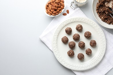 Photo of Tasty chocolate candies with nuts and ingredients on white table, flat lay. Space for text