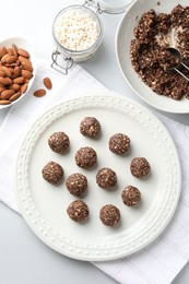 Photo of Tasty chocolate candies with nuts and ingredients on white table, flat lay