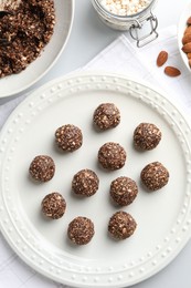 Photo of Tasty chocolate candies with nuts and ingredients on white table, flat lay