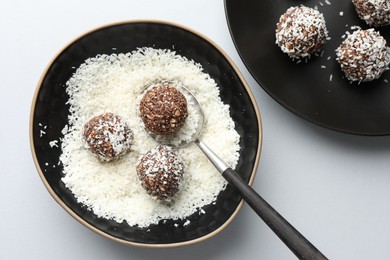 Photo of Making tasty chocolate candies with nuts and coconut flakes at white table, top view
