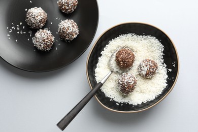 Photo of Making tasty chocolate candies with nuts and coconut flakes at white table, top view