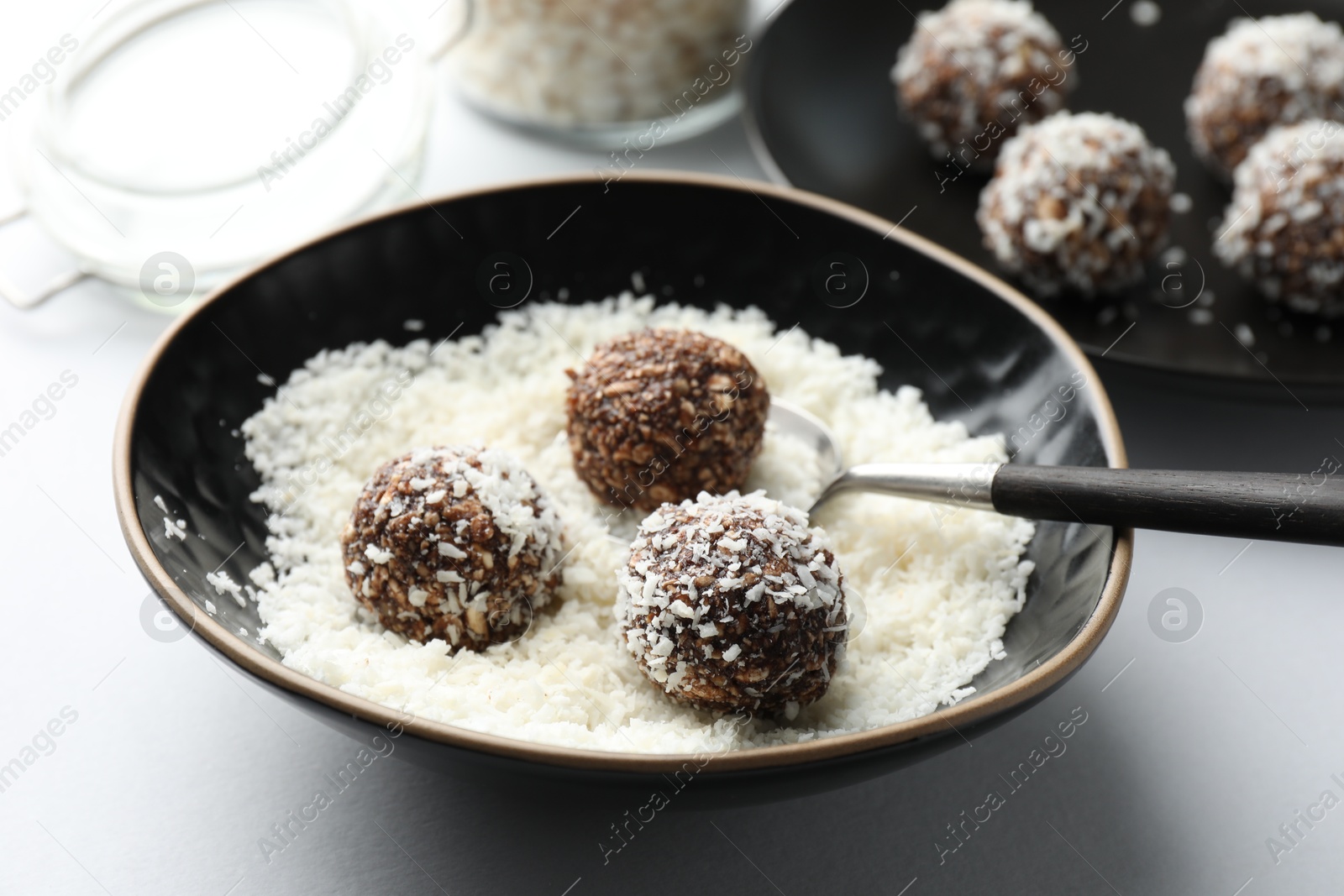 Making tasty chocolate candies with nuts and coconut flakes at white table, closeup Photo of Making tasty chocolate candies with nuts and coconut flakes at white table, closeup