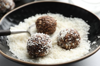 Photo of Making tasty chocolate candies with nuts and coconut flakes at white table, closeup