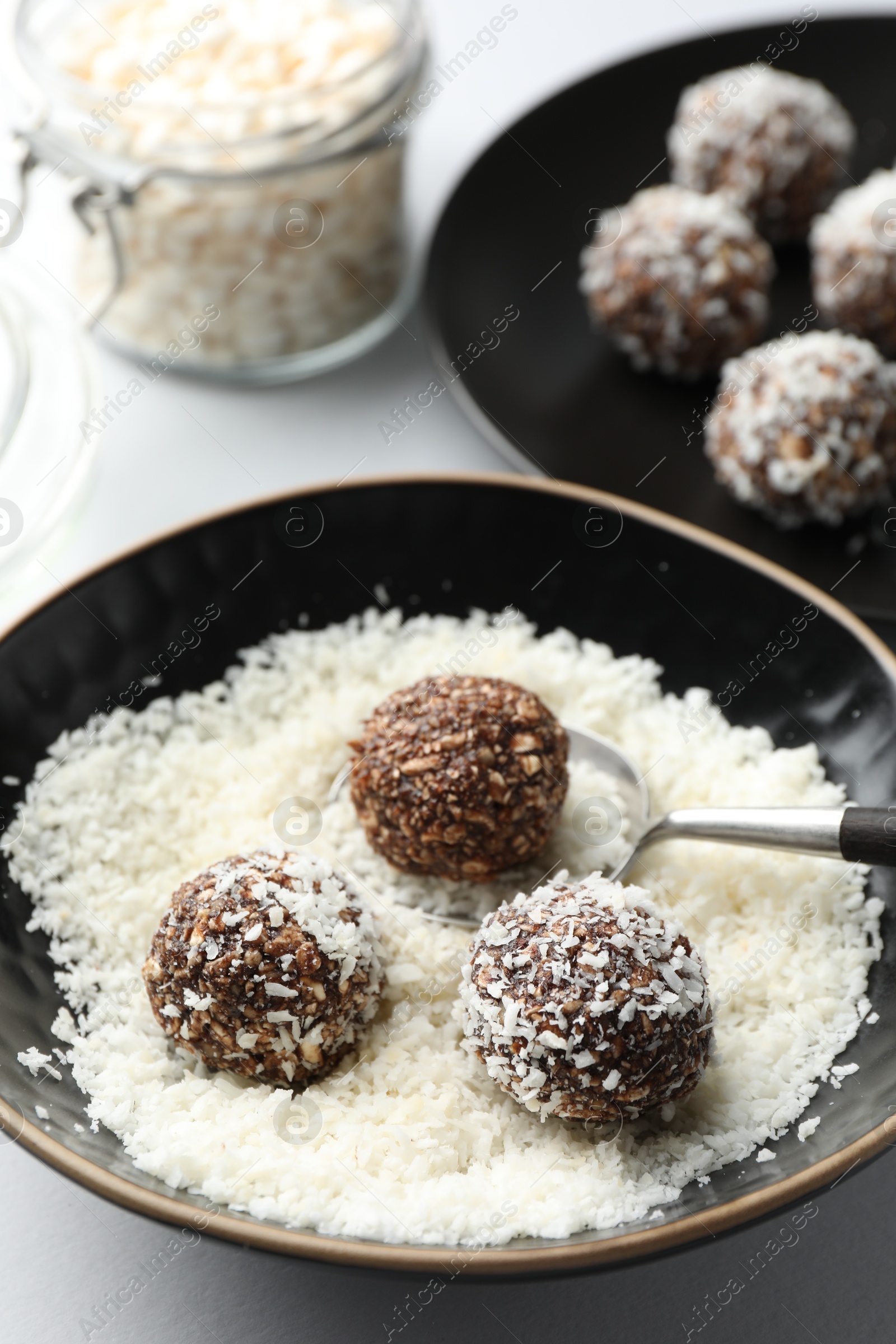 Making tasty chocolate candies with nuts and coconut flakes at white table, closeup Photo of Making tasty chocolate candies with nuts and coconut flakes at white table, closeup