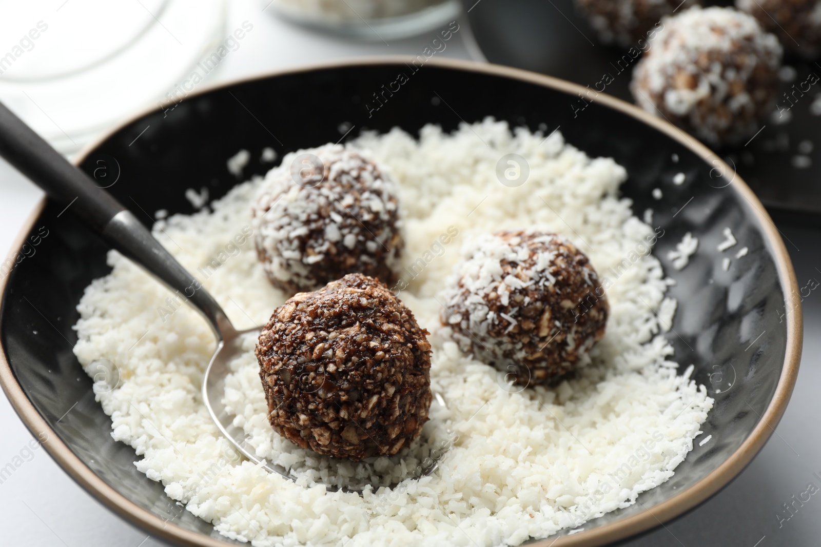 Making tasty chocolate candies with nuts and coconut flakes at white table, closeup Photo of Making tasty chocolate candies with nuts and coconut flakes at white table, closeup