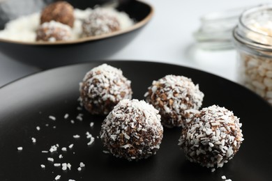 Photo of Tasty chocolate candies with coconut flakes on white table, closeup
